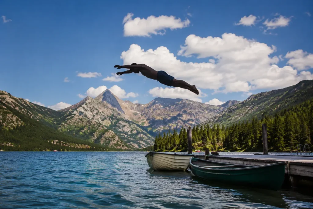 Man diving off dock at Grand Lake Colorado with Rocky Mountain National Park peaks in background