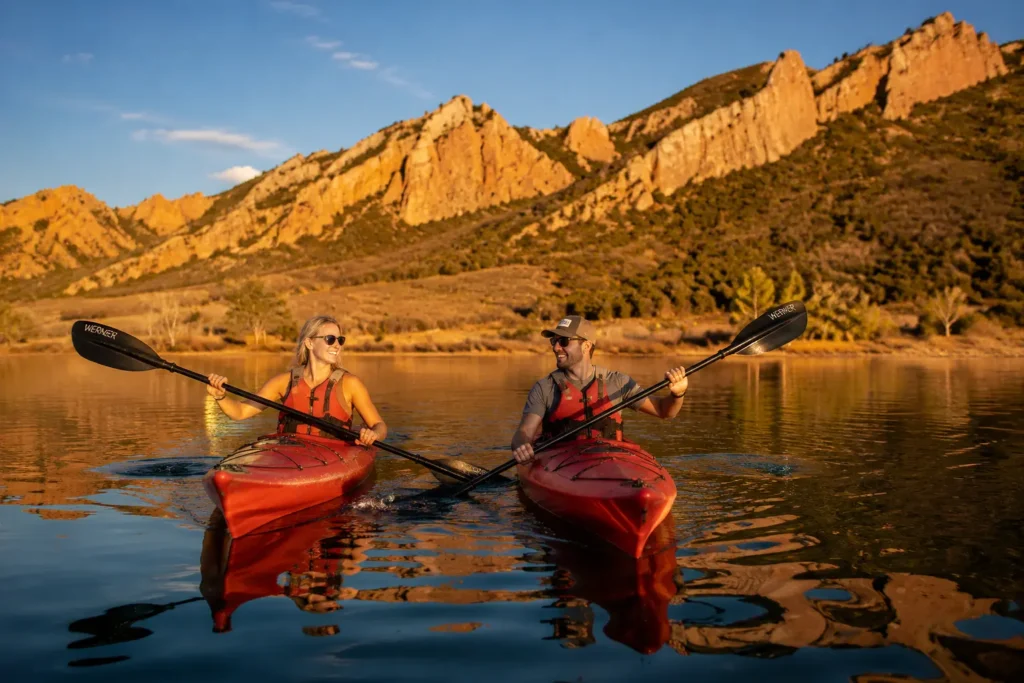 Couple kayaking on Horsetooth Reservoir at golden hour with red rock ridgelines in Fort Collins Colorado