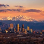 Denver, Colorado Mountains: Your Complete Visitor Guide. Denver skyline at sunset with the snow-capped Front Range mountains rising behind downtown