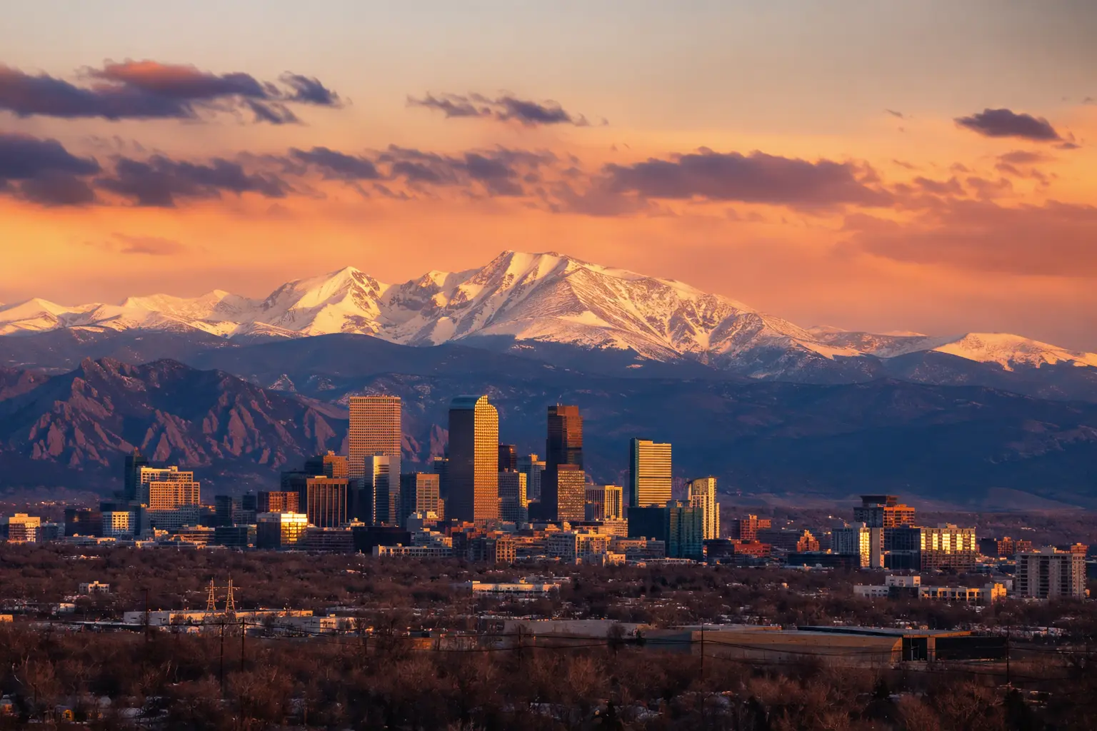 Denver, Colorado Mountains: Your Complete Visitor Guide. Denver skyline at sunset with the snow-capped Front Range mountains rising behind downtown